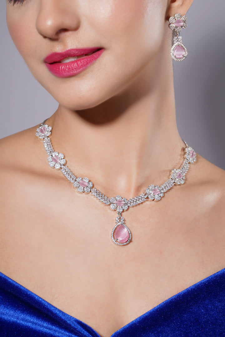 Close-up of a woman wearing a pink gemstone necklace and earrings with a blurred background