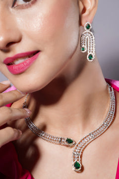 Close-up of a woman wearing a diamond necklace and earrings with emerald stones.