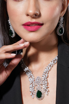 Close-up of a woman wearing a diamond and emerald necklace and earrings.