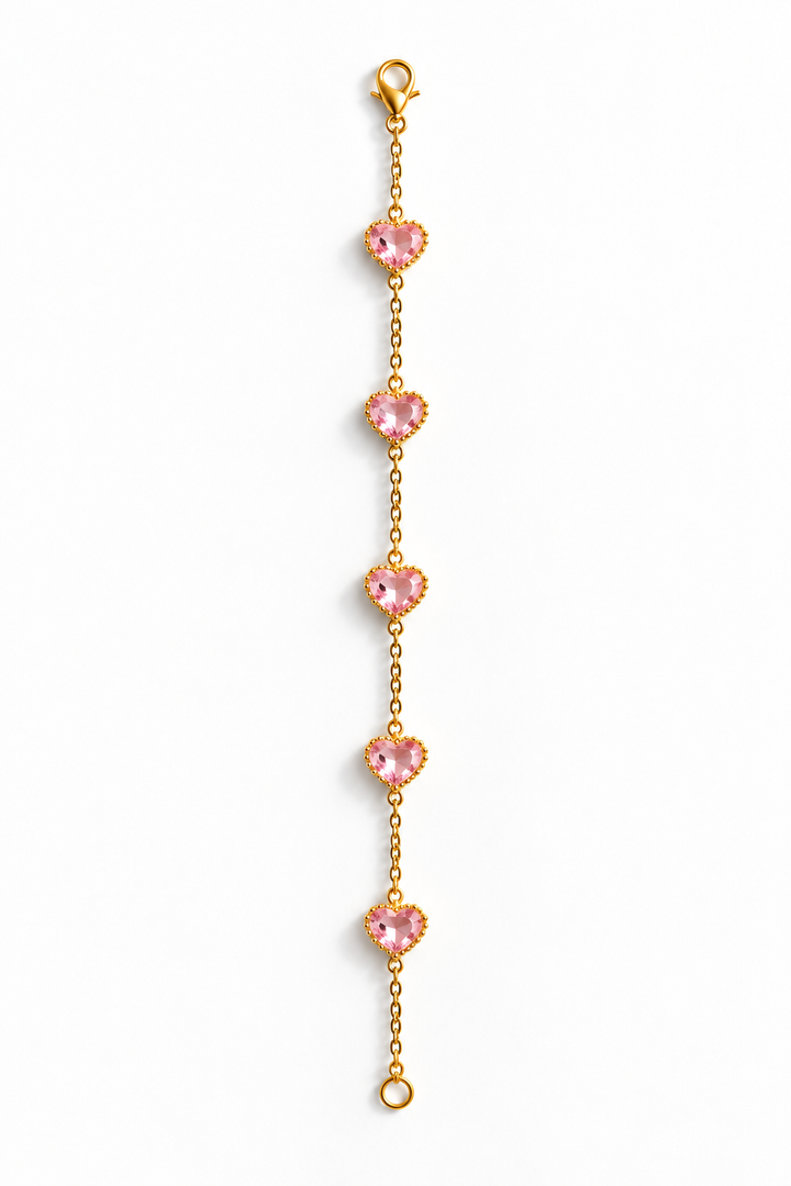 A delicate gold chain bracelet featuring five evenly spaced, heart-shaped pink gemstones, displayed vertically on a clean white background.
