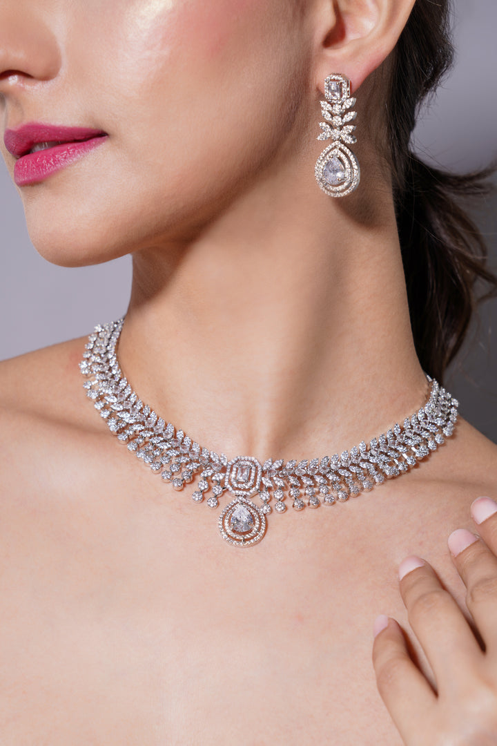 Silver necklace and earrings on a model with a neutral background