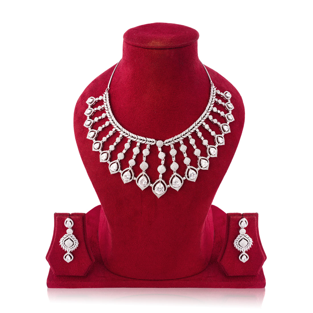 Silver necklace and earrings set on a red velvet stand with a white background