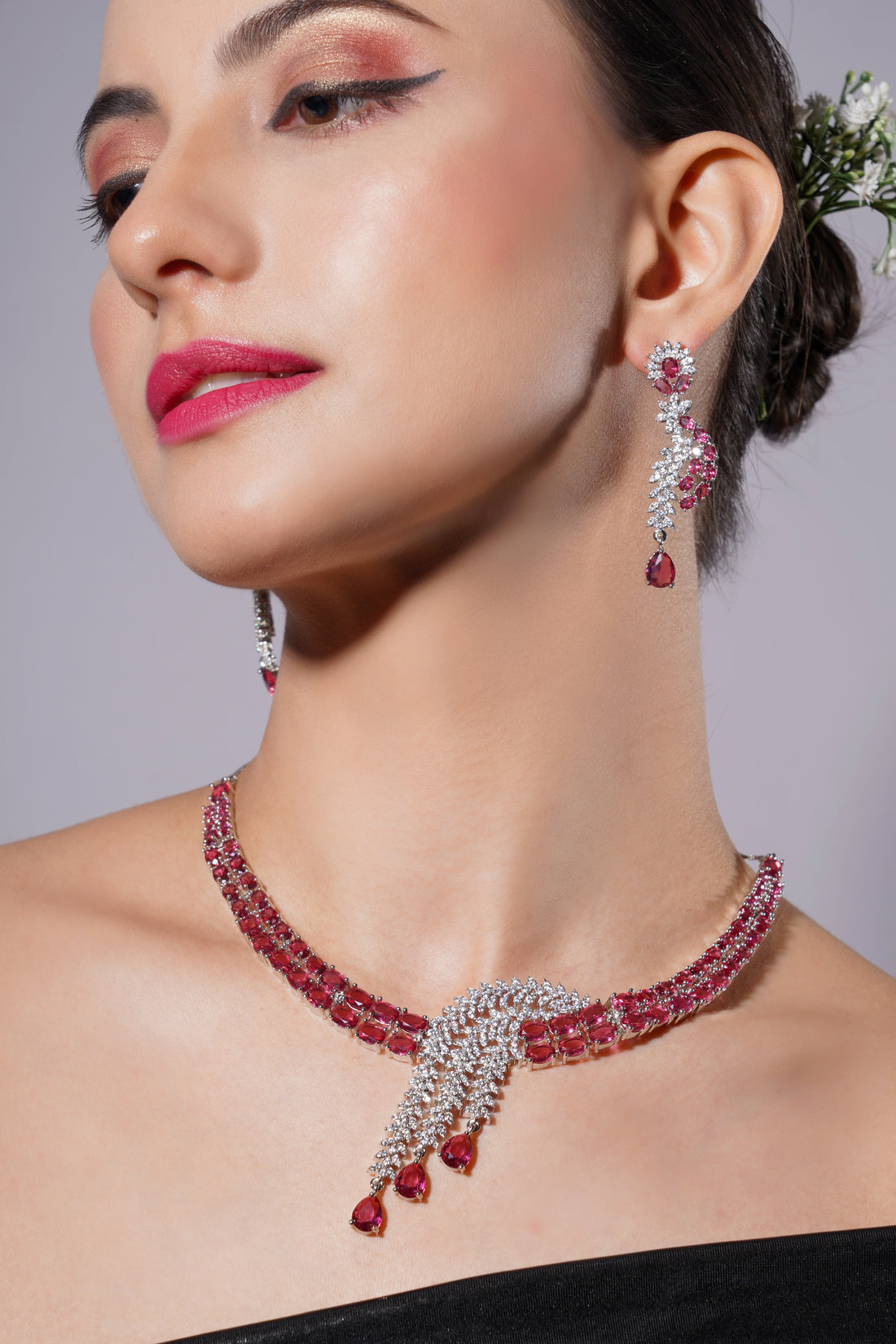 Woman wearing a red and silver jewelry set with a gray background