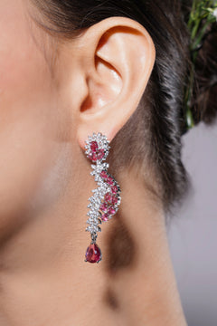 Close-up of a woman's ear wearing a sparkling earring with pink gemstones.