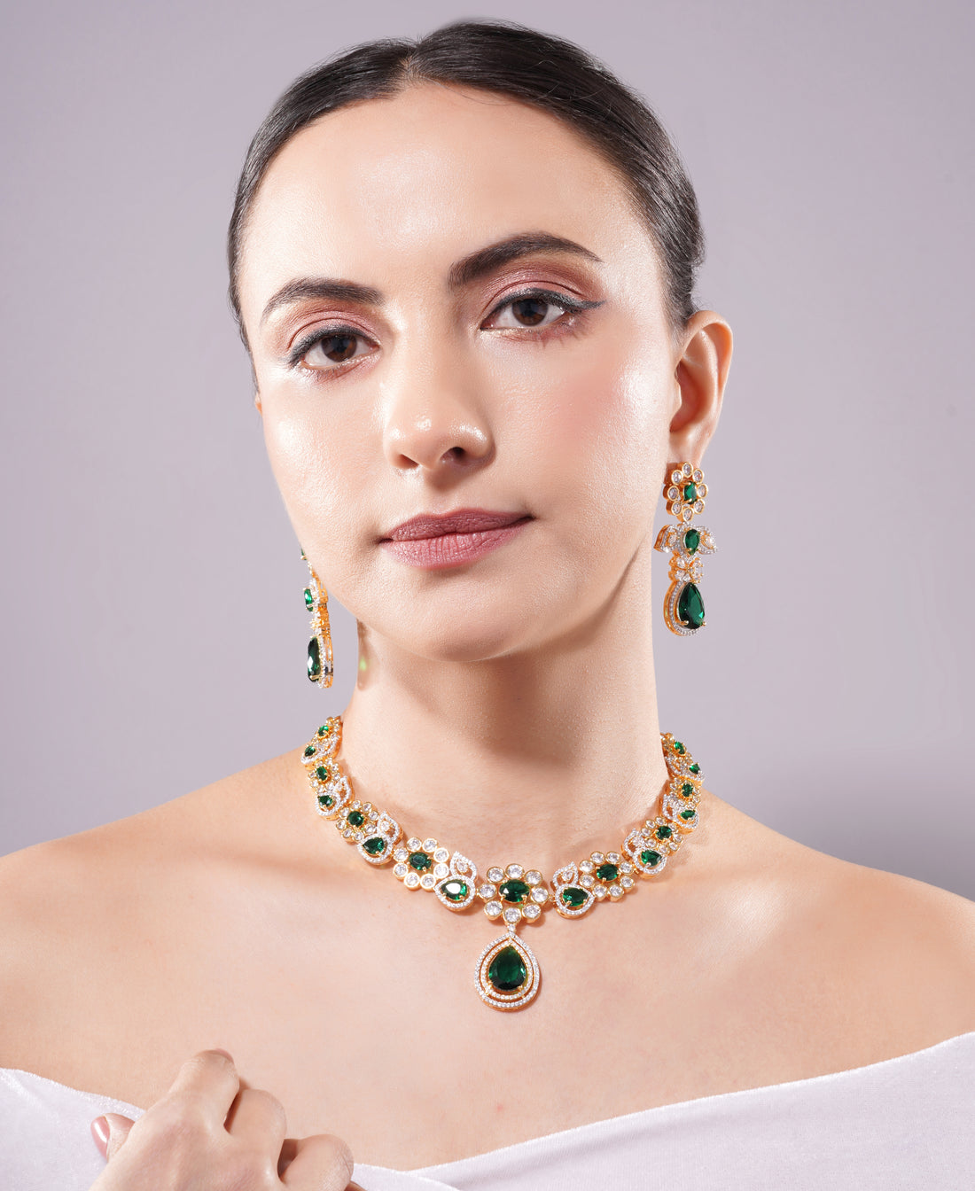 Woman wearing a green gemstone necklace and earrings on a gray background