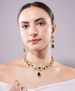 Woman wearing a green gemstone necklace and earrings on a gray background