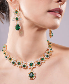 Emerald and diamond necklace with matching earrings on a model against a neutral background