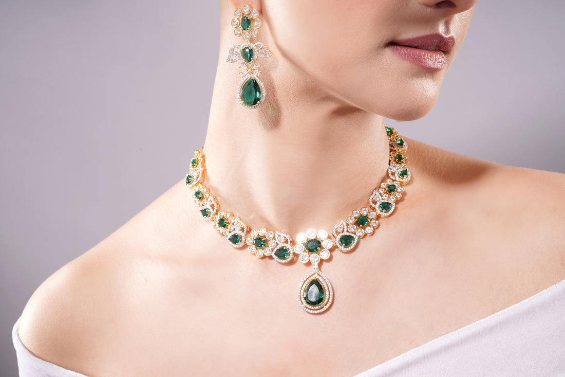 Emerald necklace and earrings on a model against a gray background