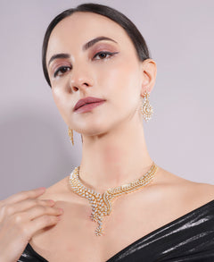 Woman wearing a gold necklace and earrings against a gray background