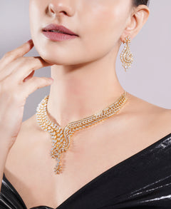 Woman wearing a gold necklace and earrings on a plain background