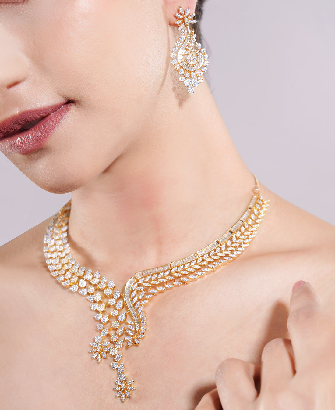 Gold necklace and earrings on a model against a neutral background