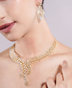 Gold necklace and earrings on a model against a neutral background