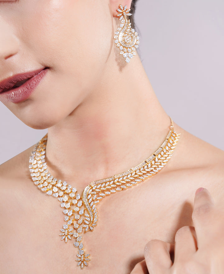 Gold necklace and earrings on a model against a neutral background