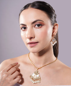 Woman wearing a gold necklace and earrings against a gray background