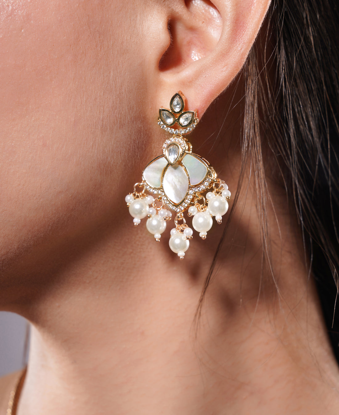 Close-up of a woman wearing a gold and pearl earring.