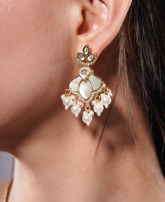 Close-up of a woman wearing a gold and pearl earring.