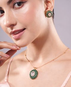 Close-up of a woman wearing a necklace and earrings with green gemstones on a neutral background