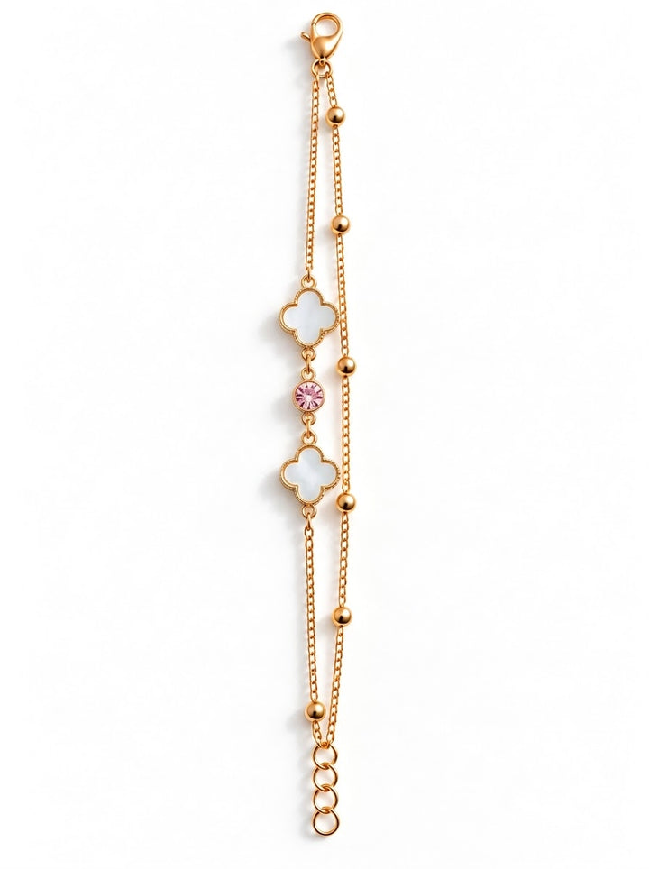 A delicate rose gold chain bracelet featuring two white enameled clover motifs and a small pink gemstone accent, displayed on a clean white background.