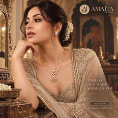 A woman in an ornate beige embellished traditional outfit wears a gold layered necklace and matching earring with white floral hair accessories, posed in a luxurious interior with gold-toned decor. Amaita Jewels branding and promotional text appear on the image.