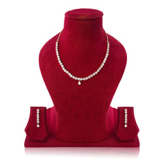 Red velvet jewelry display with a necklace and earrings on a white background