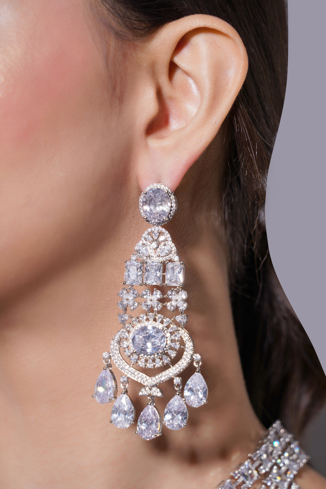 Close-up of a woman wearing a sparkling diamond earring against a neutral background