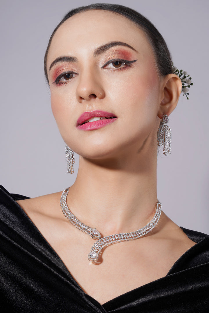 Woman wearing a diamond necklace and earrings against a gray background