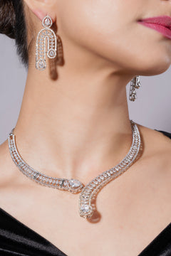 Close-up of a person wearing a sparkling diamond necklace and earrings against a neutral background