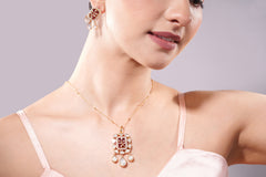 Close-up of a woman wearing a gold necklace and earrings on a gray background
