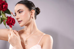 Woman wearing a gold necklace with red roses in the background