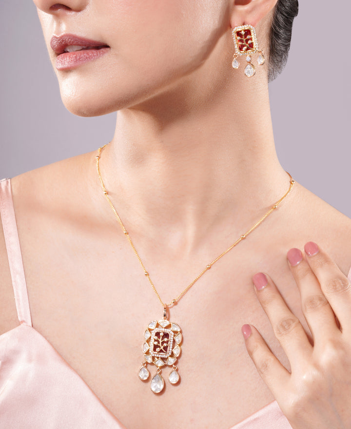 Close-up of a woman wearing a gold necklace and earrings on a light gray background