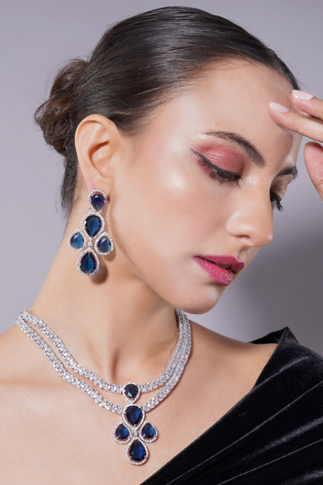 Woman wearing a blue and silver jewelry set against a neutral background