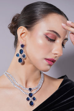 Woman wearing a blue and silver jewelry set against a neutral background