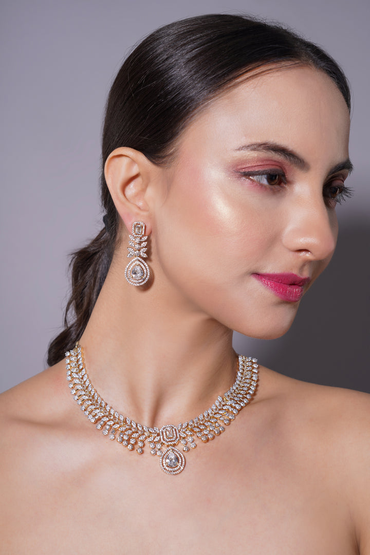 Woman wearing a diamond necklace and earrings against a gray background