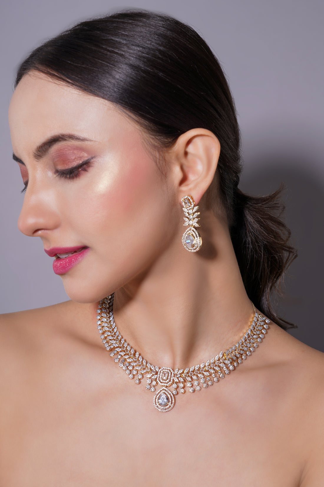 Woman wearing a necklace and earrings on a gray background