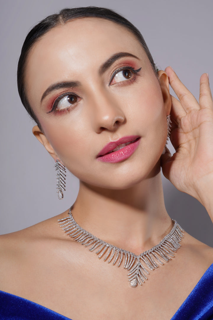 Woman wearing a sparkling necklace and earrings against a gray background