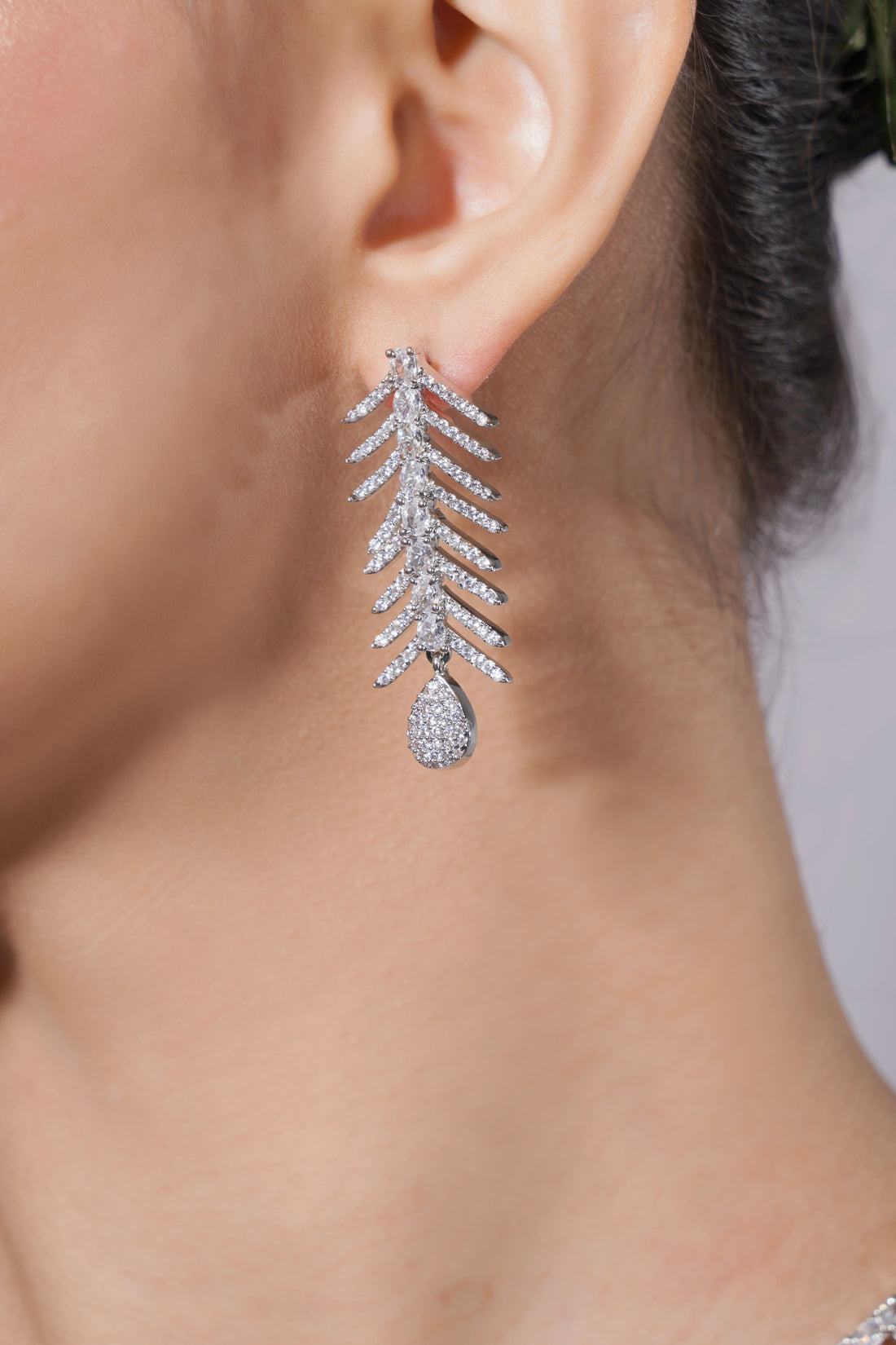 Silver earrings with a teardrop design worn by a person.