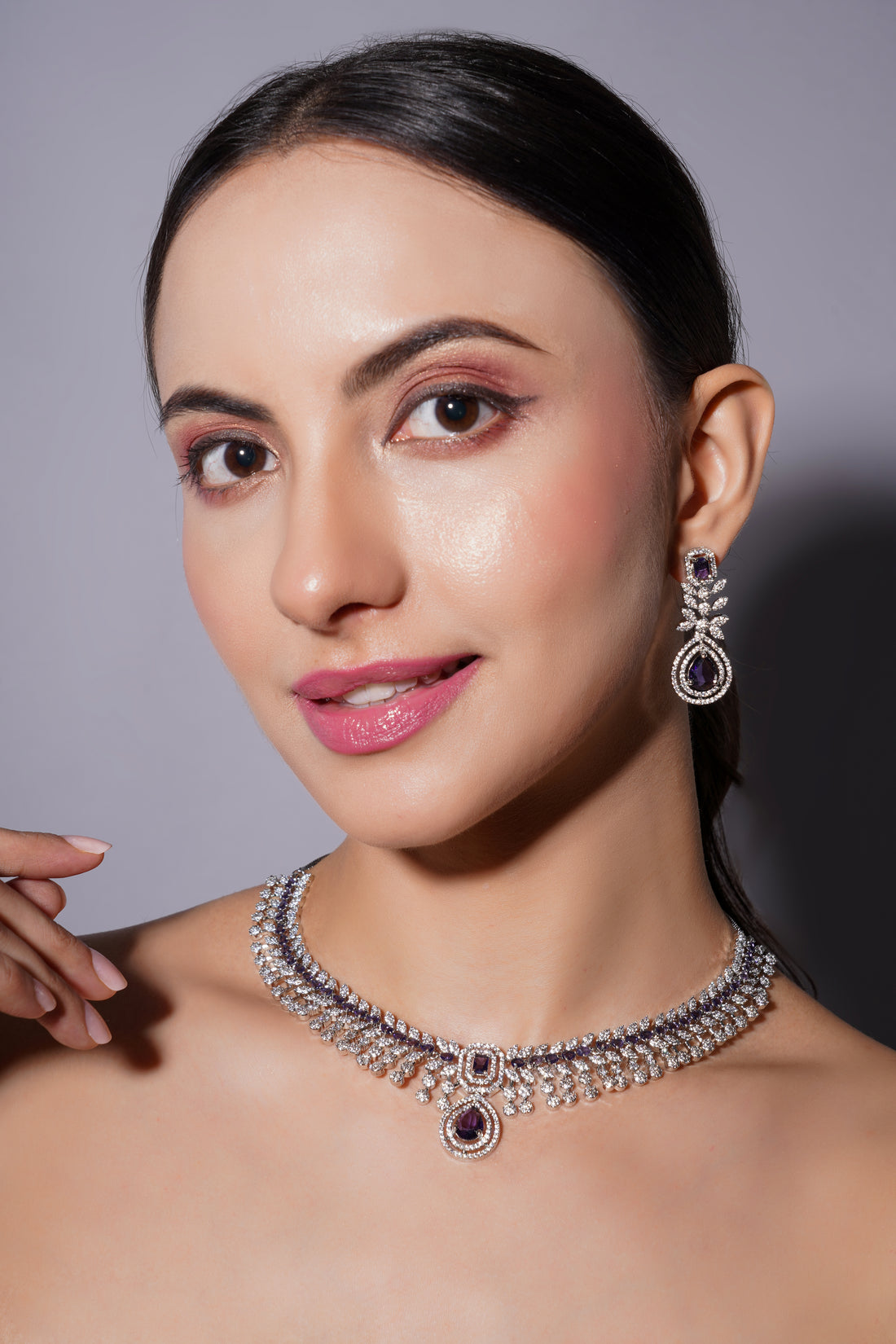 Woman wearing a diamond necklace and earrings on a gray background