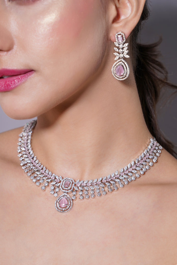 Close-up of a woman wearing a diamond necklace and earrings with pink gemstones.